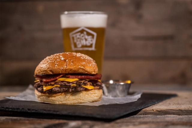 A barbecue meat sandwich sits in front of a pint of Tool Shed beer.