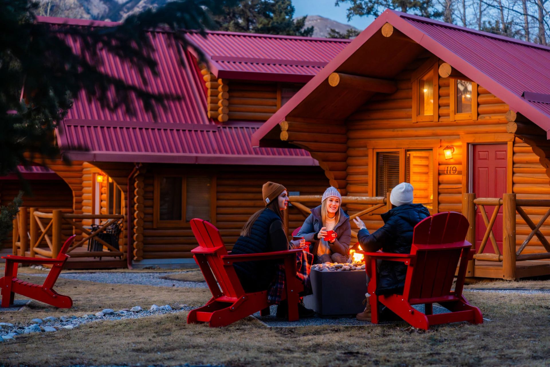 Friends enjoying a beverage around the campfire a Miette Mountain Cabins.