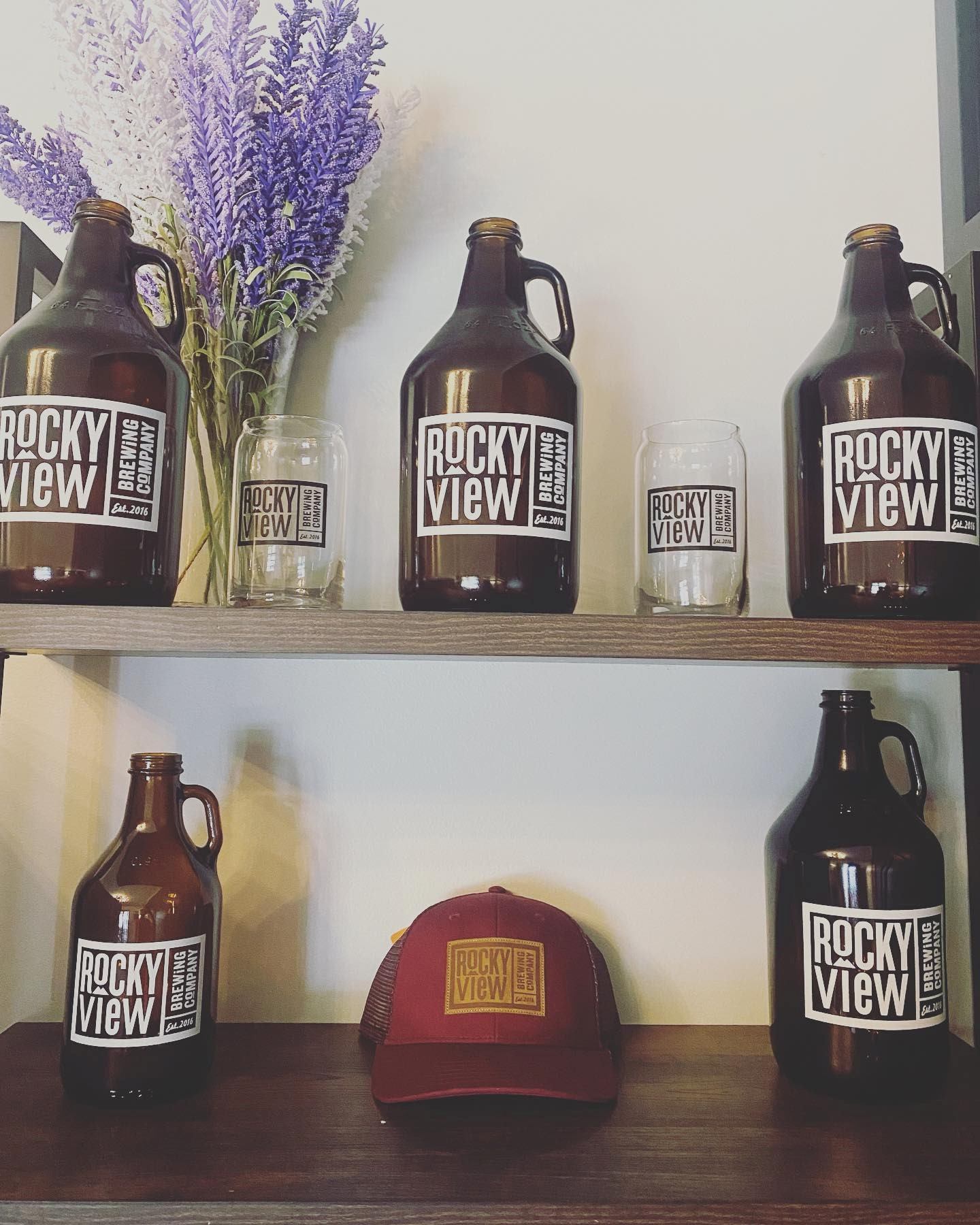 Shelves with Rocky View Brewing Company merchandise on them. Growlers and a hat.