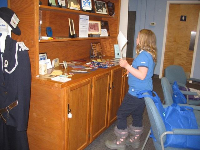 Person in blue shirt views wooden display shelves and museum artefacts.