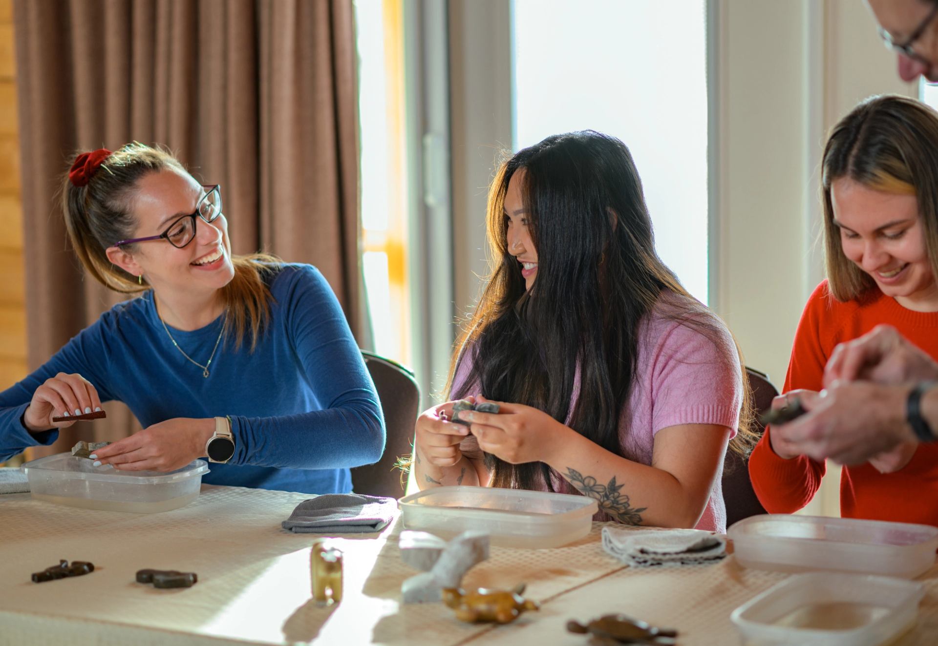 Group shapes clay pieces around a table during a pottery activity.