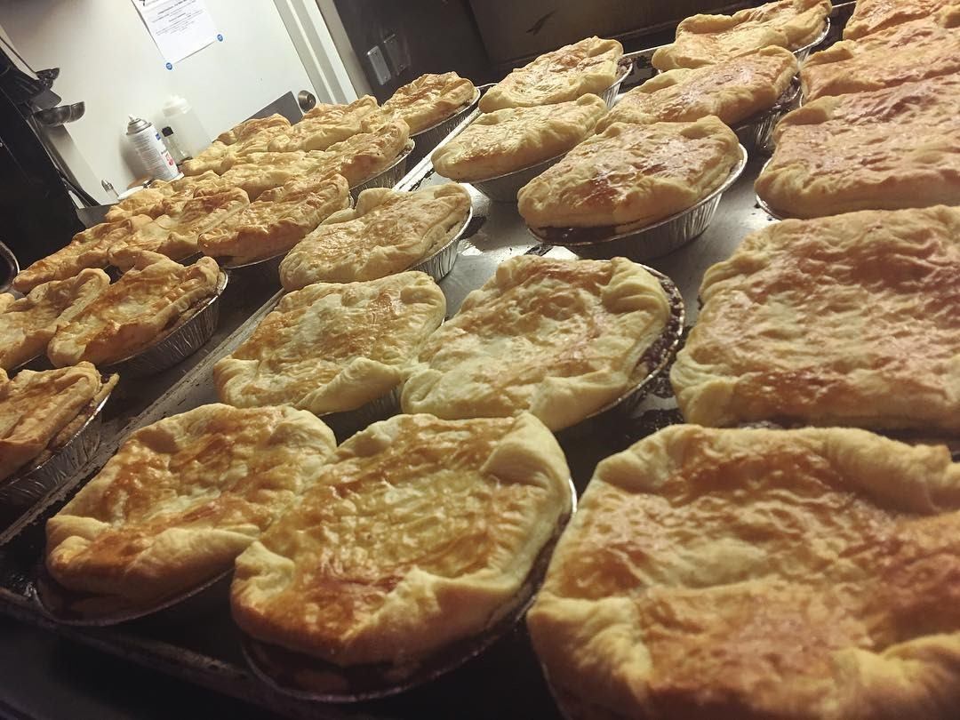 Tray of baked flatbreads stacked in rows with crimped edges and golden crusts.