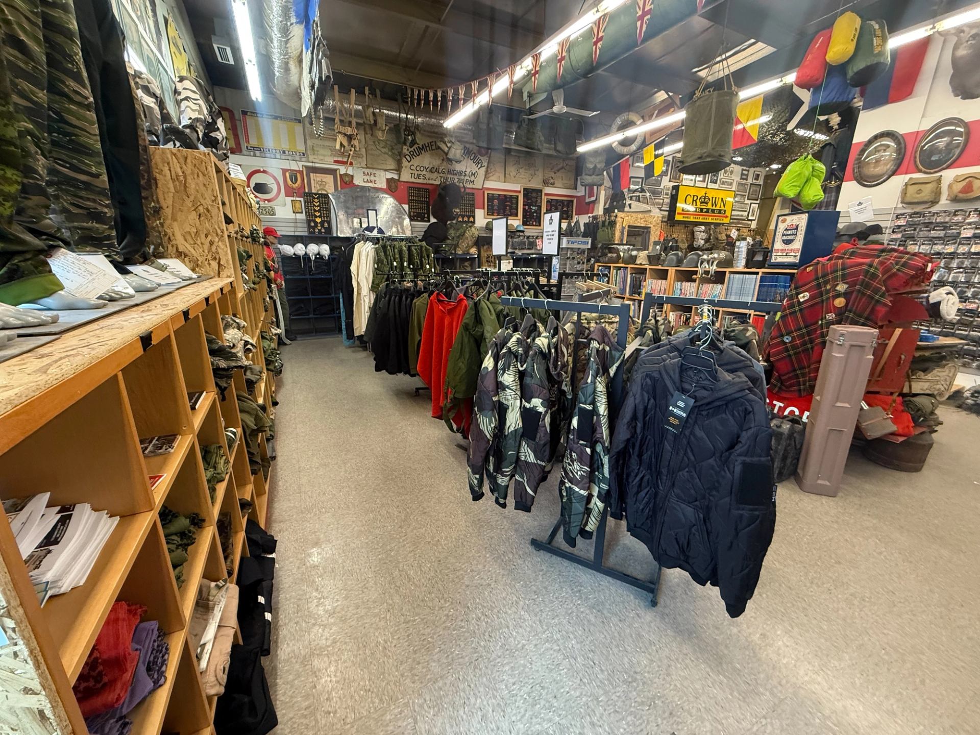 Crown Surplus Store displays racks of jackets, shelves of gear, books, and military accessories throughout.