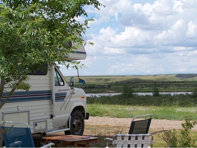 RV parked at Peter Fidler Park with chairs and a scenic prairie view.