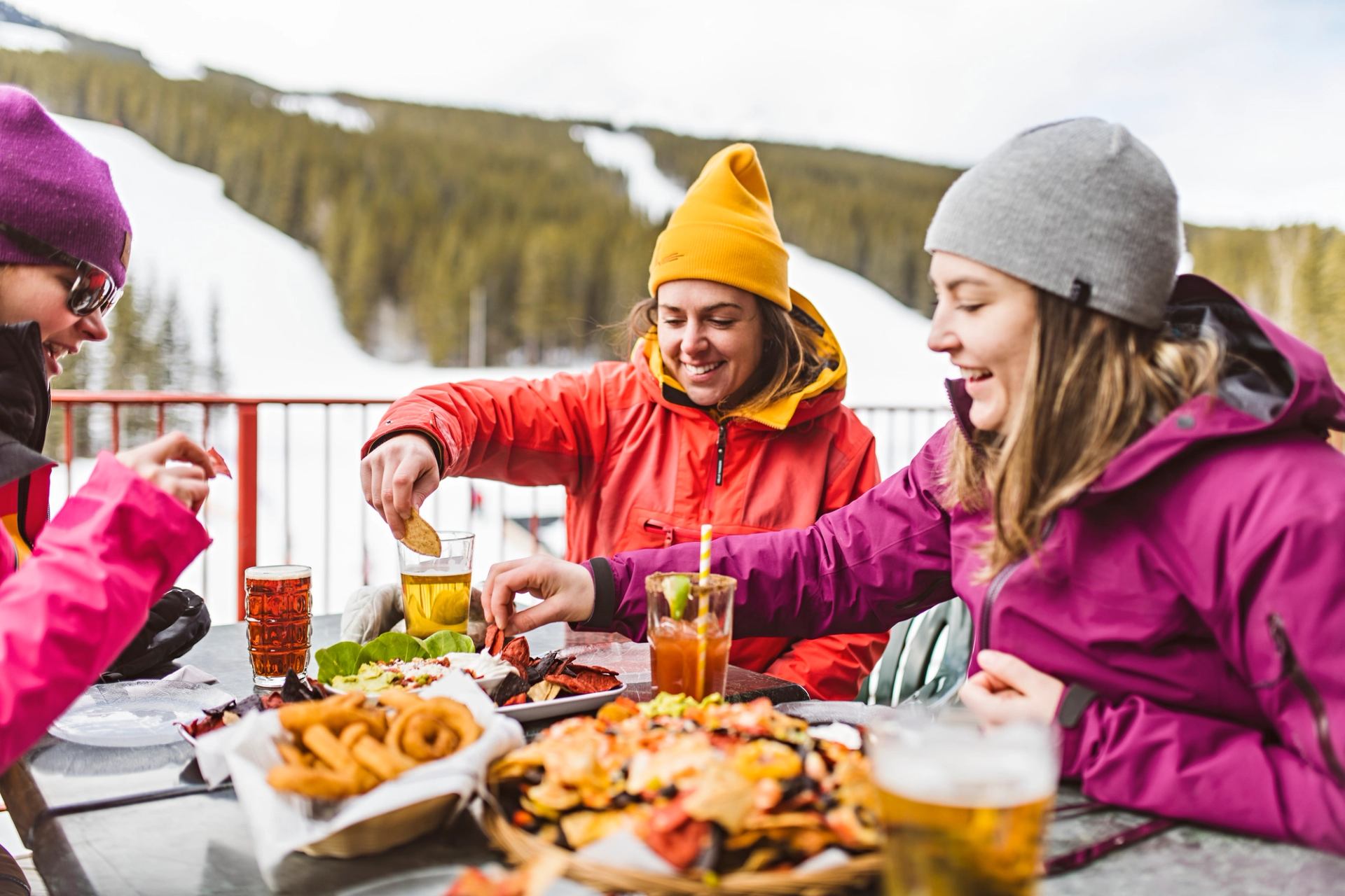 Friends enjoying appetizers and drinks on an outdoor patio, after skiing at Nakiska in Kananaskis Country