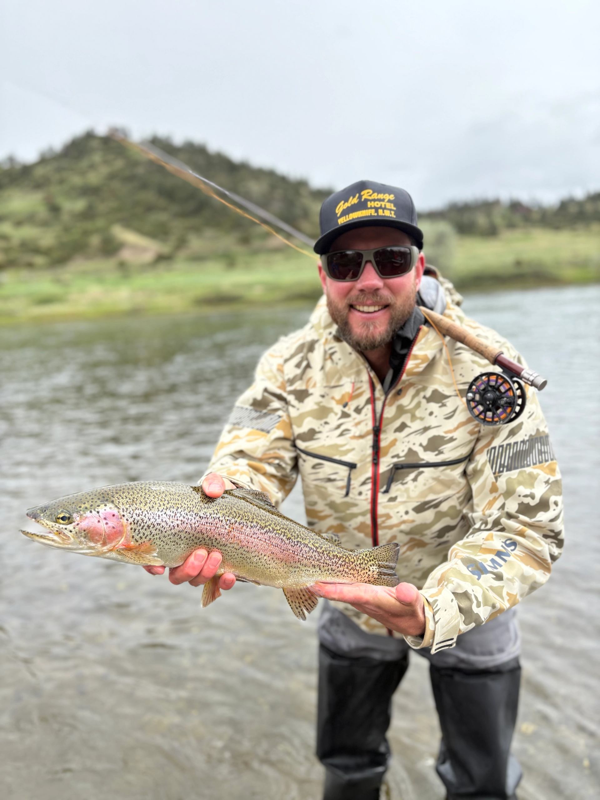 A man standing in the river holding his catch