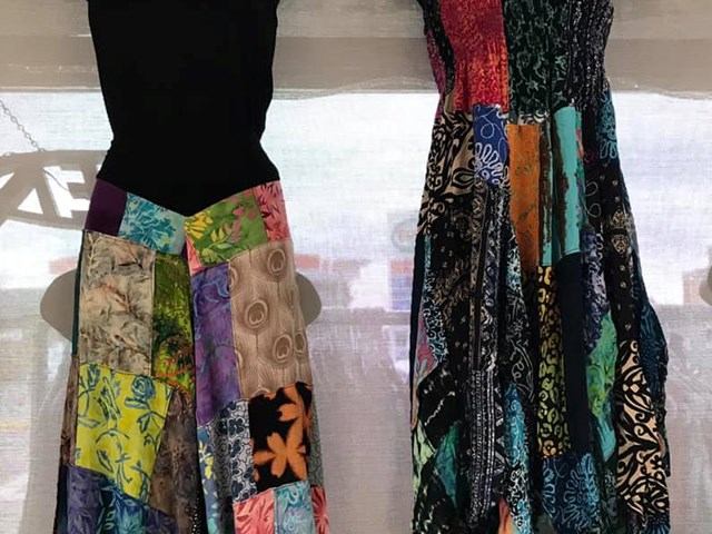 Patchwork skirt on mannequin beside long patterned dress on display.