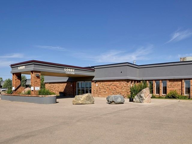 Hotel lobby entrance with brick facade and driveway in front under blue sky.