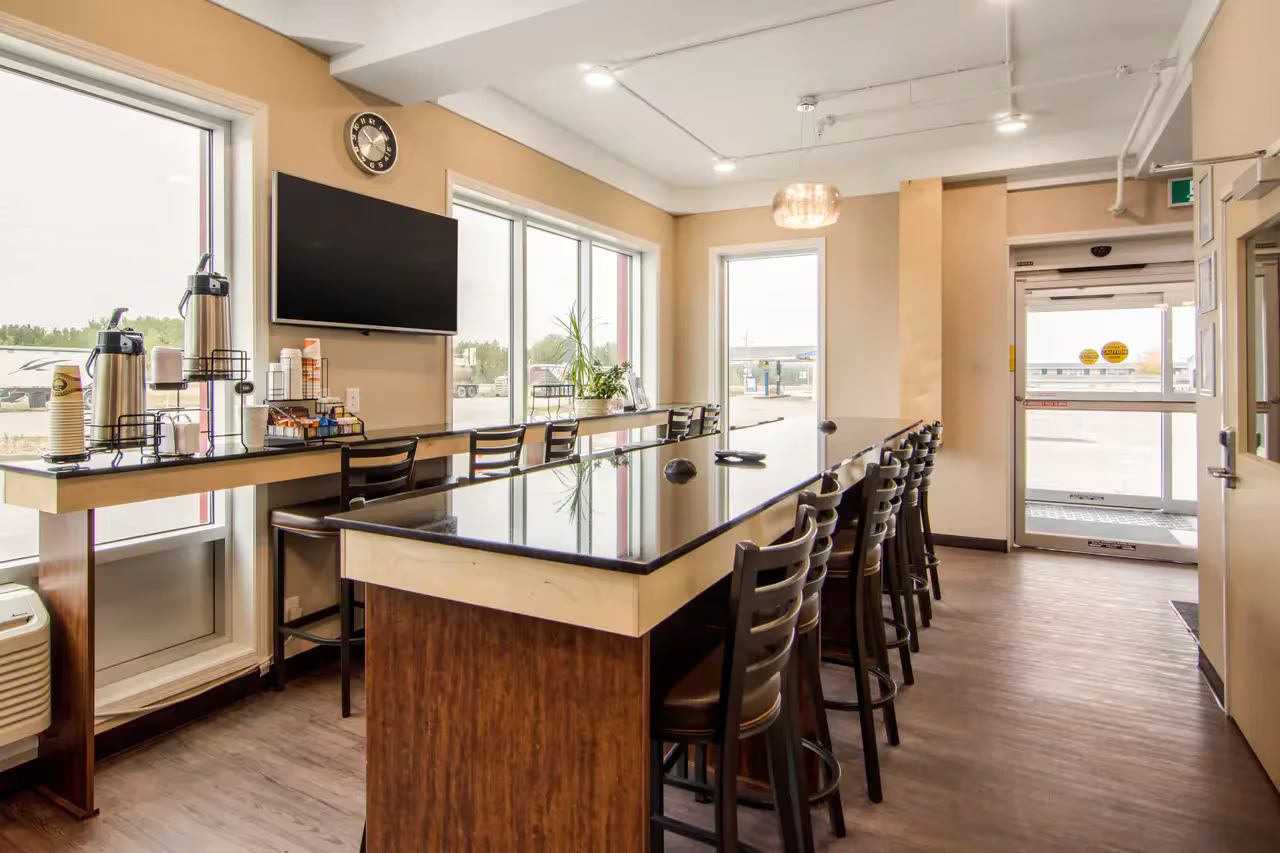 Breakfast area with high-top counter, chairs, coffee station, and large windows
