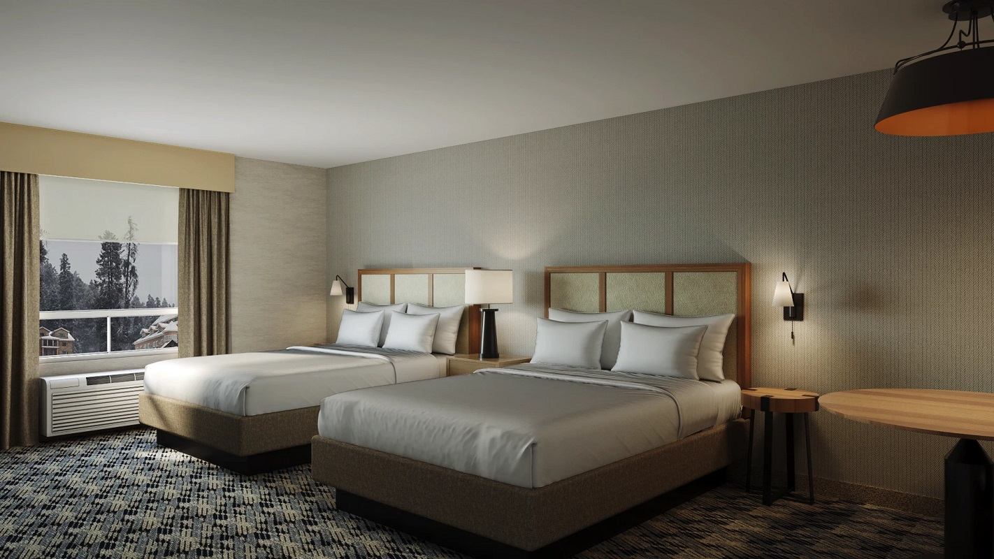Hotel room with two made beds, bedside lamps, window and small round table.