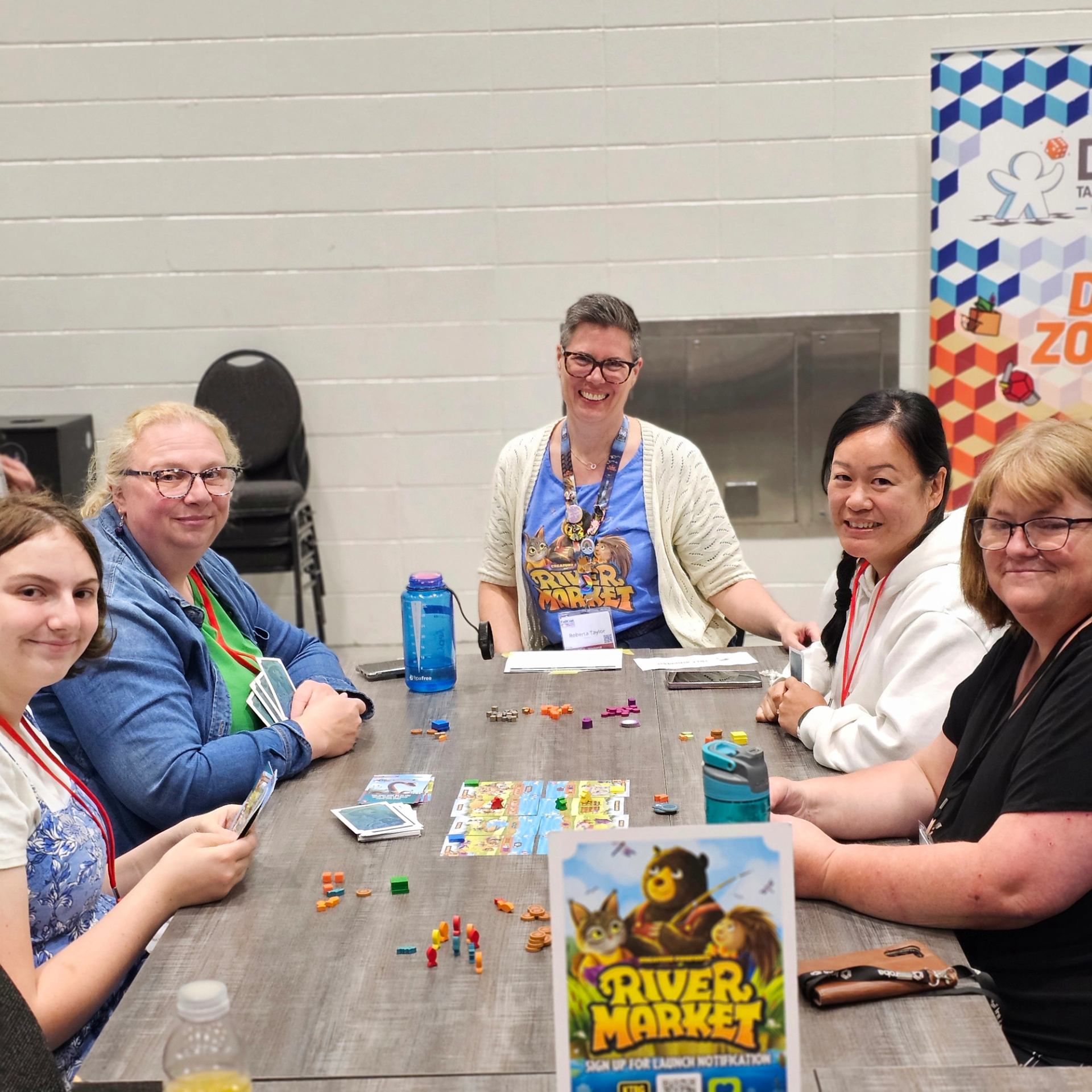 Group of people playing River Market board game at a convention table.