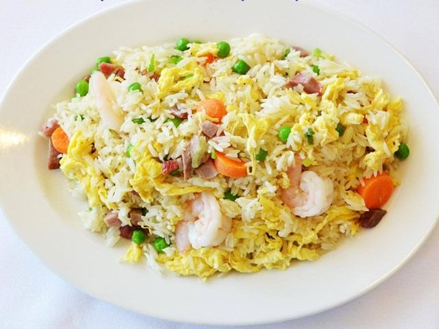Shrimp fried rice with vegetables on a white plate.