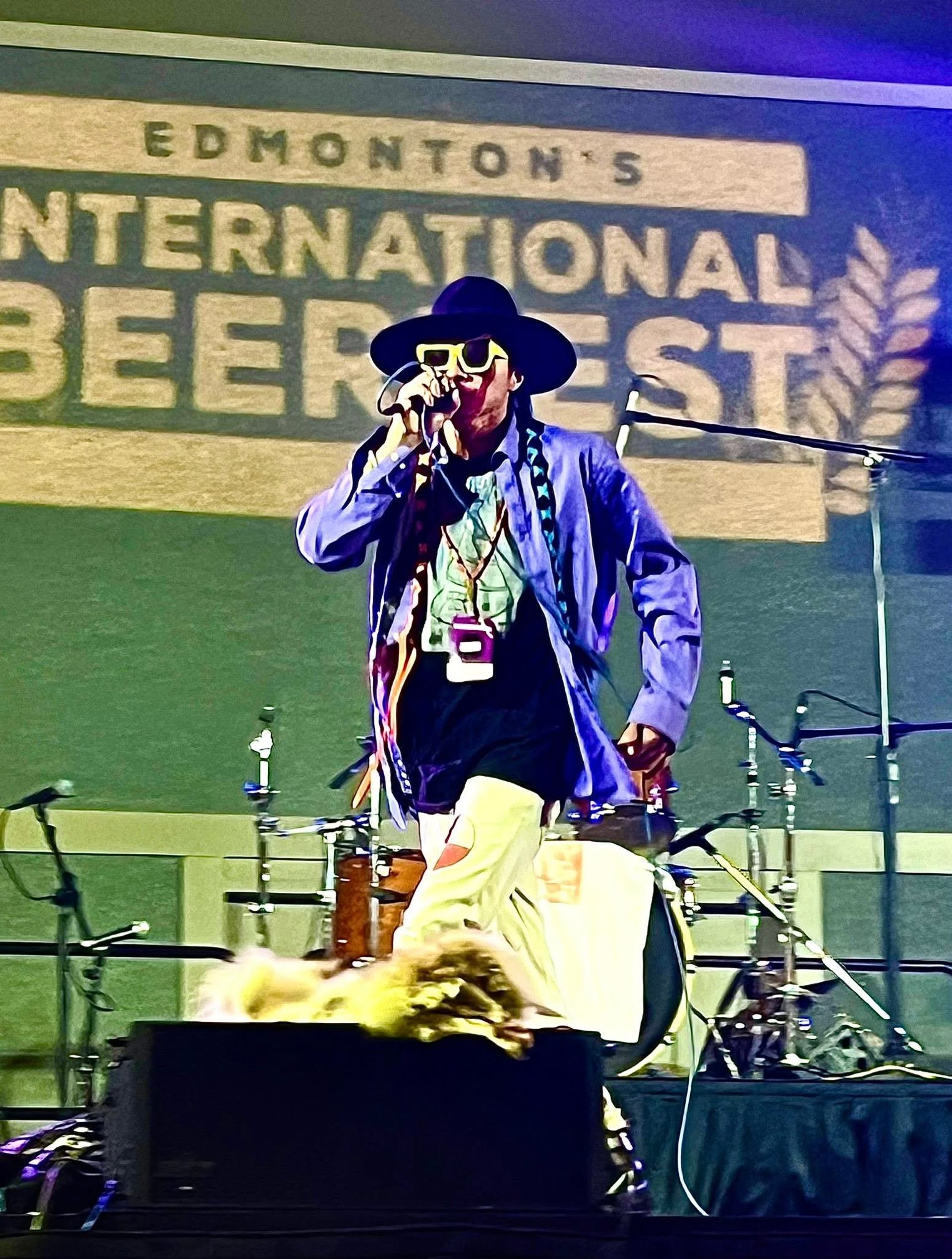 Performer in vibrant outfit singing on stage at Edmonton’s International Beerfest.