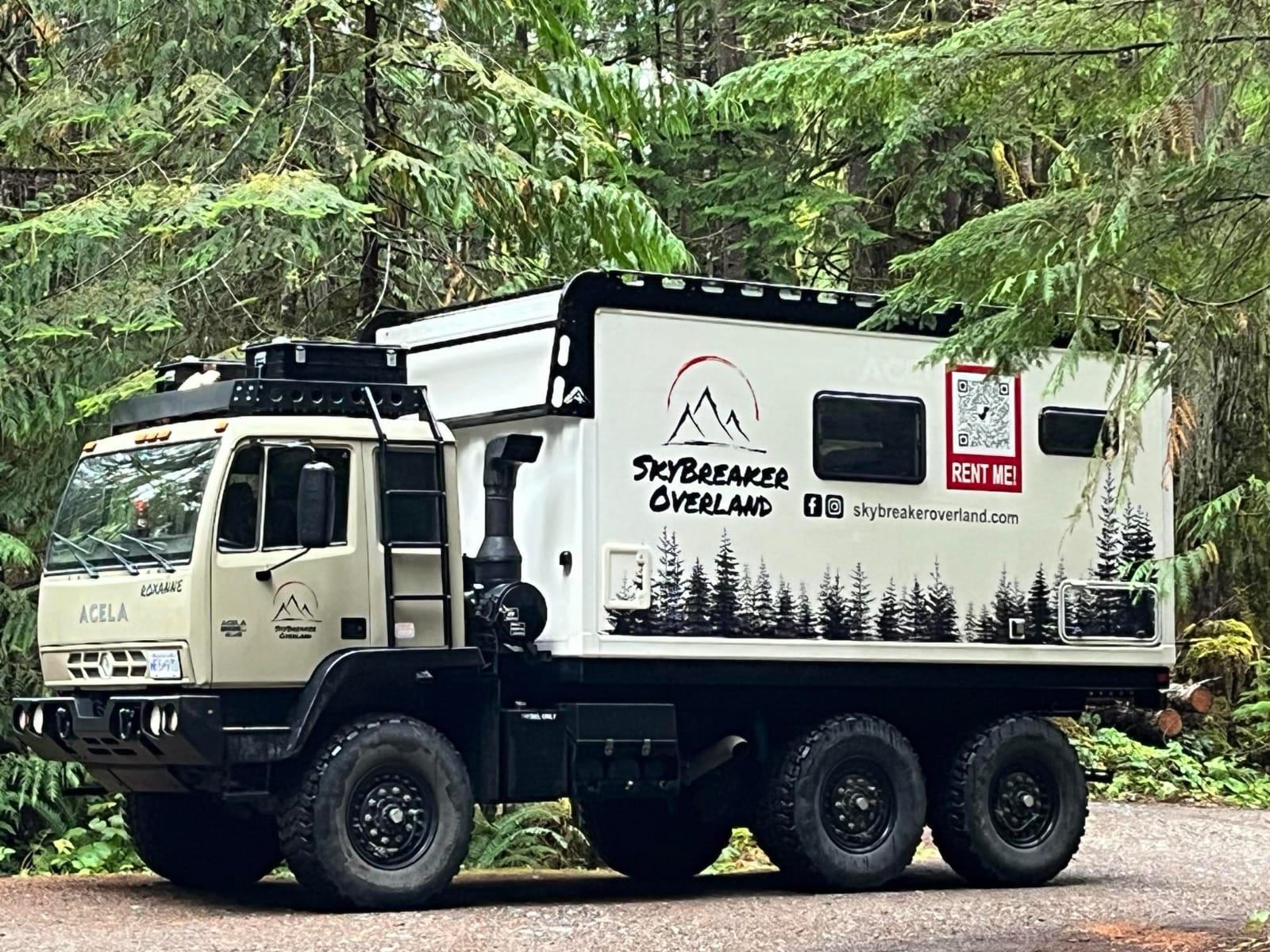 Rugged six-wheel expedition truck parked in forest with SkyBreaker Overland branding.