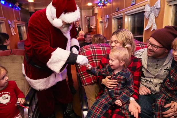 Santa on the train handing out bells to all the believers while aboard the Polar Express