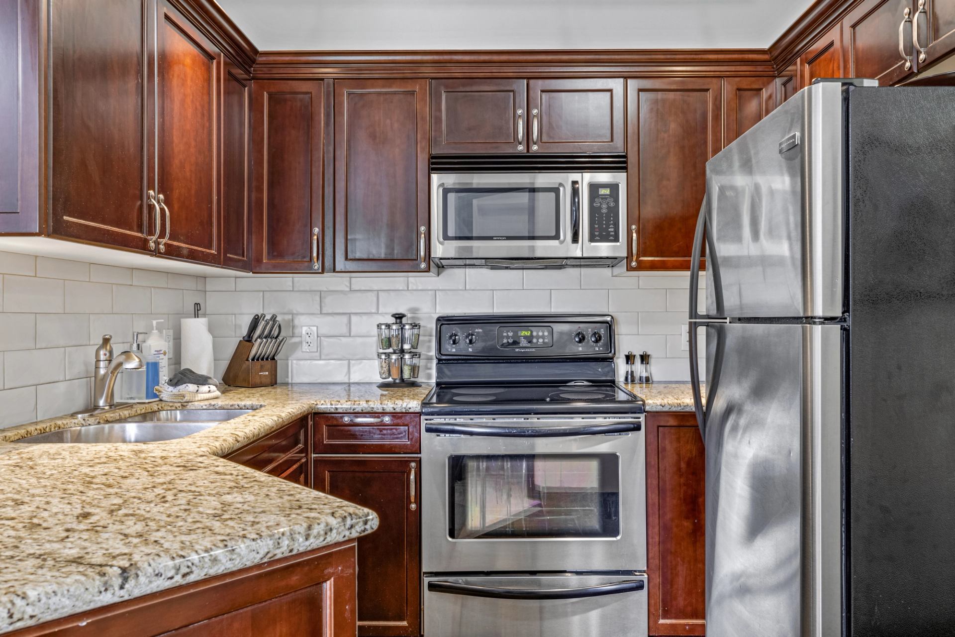 Kitchen with dark wood cabinets, granite counters and stainless steel appliances.