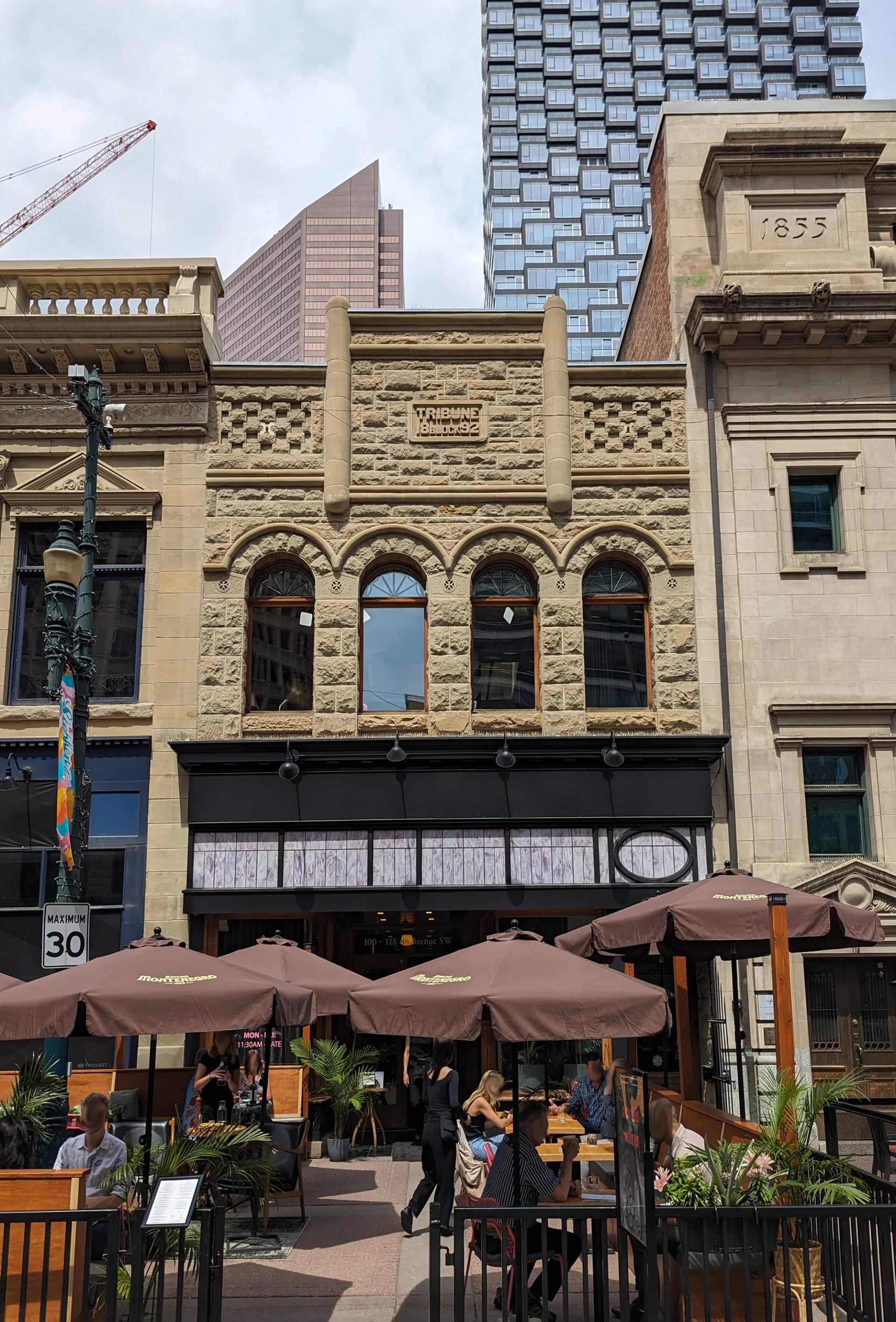 Historic Tribune Block building with busy patio restaurant and umbrellas on downtown street.