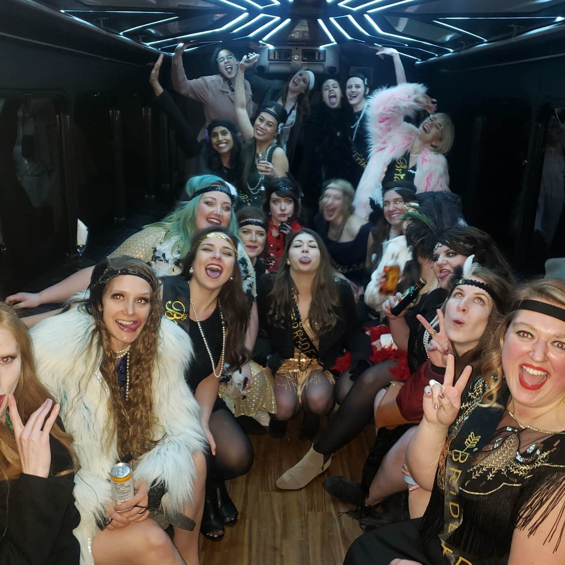 Costumed group partying under blue neon lights in a festive bus.