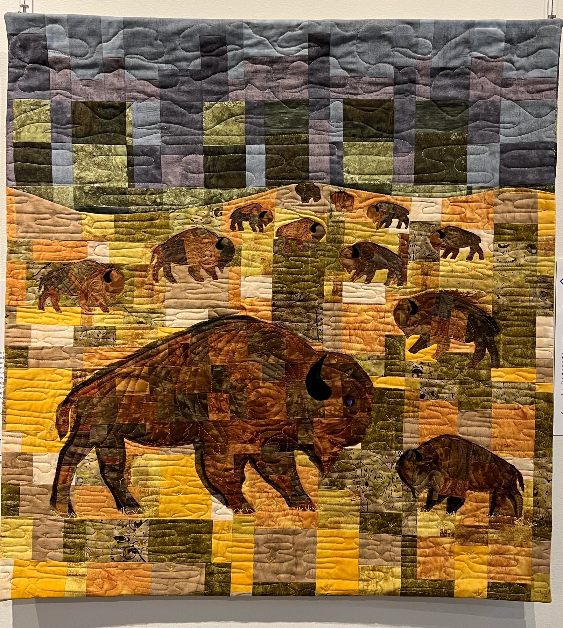 Quilt wall display showing stitched elephants, rhinos, and patchwork landscape panels.