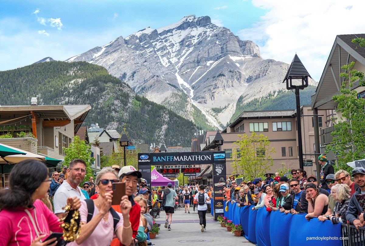 Crowd cheers at Banff Marathon with mountain backdrop.