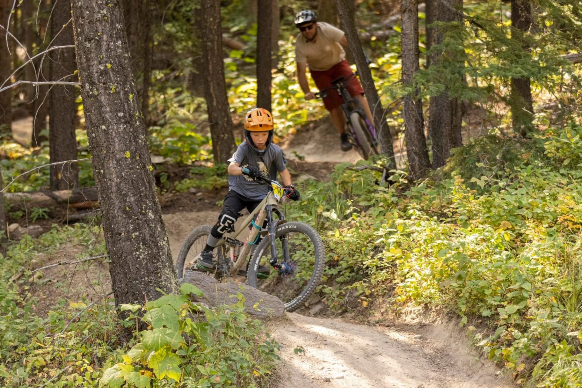 Mountain bikers ride a dirt trail through trees during an enduro race.