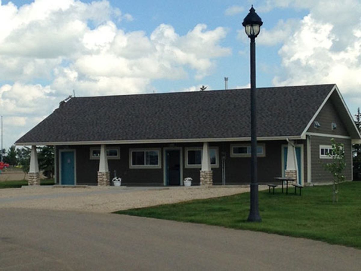 Single-storey building with a covered porch, blue doors, picnic table and lamppost.