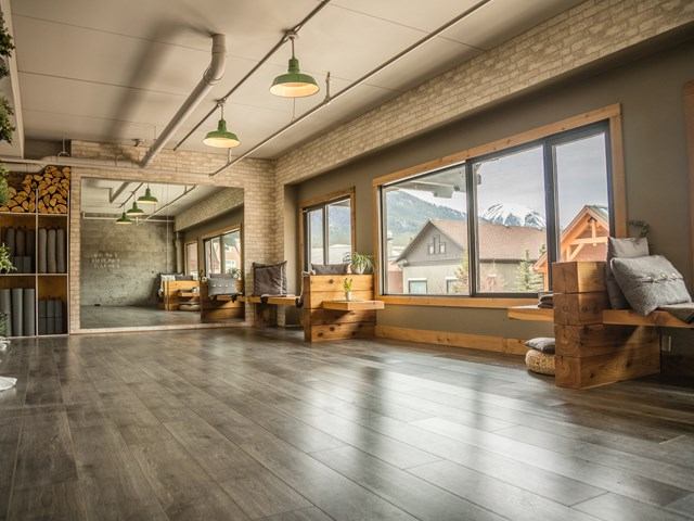 Sunlit modern room with wood floors, benches, and mountain views.