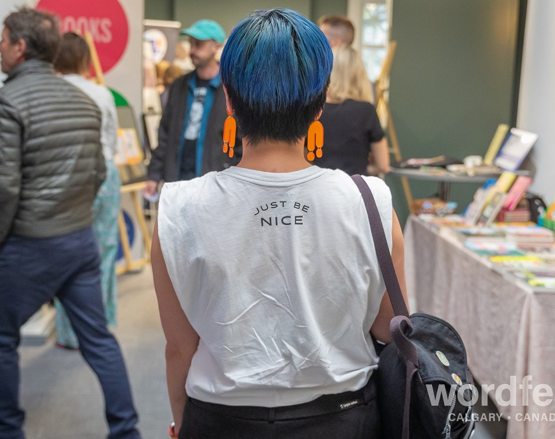 Attendee with blue hair and "Just Be Nice" shirt at Wordfest