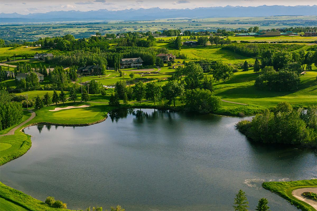 A large pond and several golf holes with mountains in the distance.