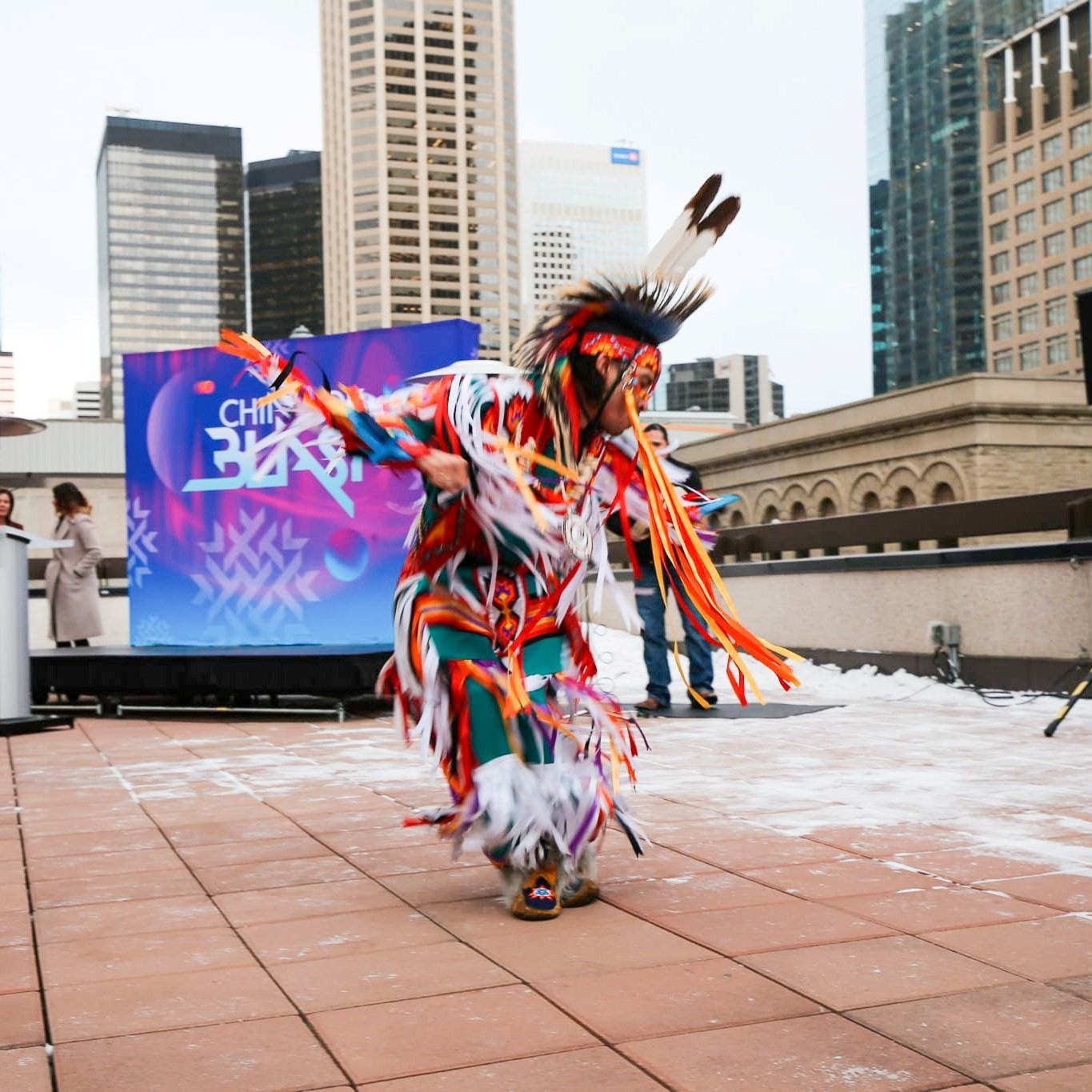 Indigenous dancer in colorful regalia performs in city