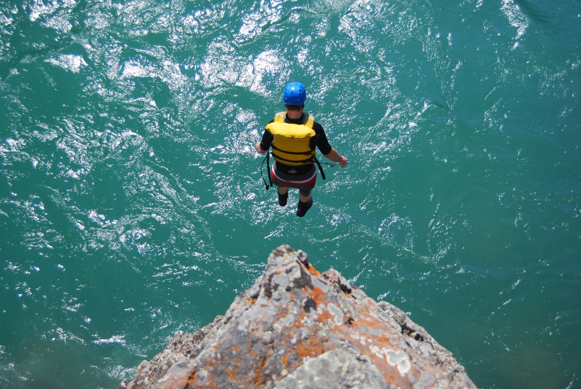 A man in a life jacket plunges into the turquoise waters of the Canadian Rockies.