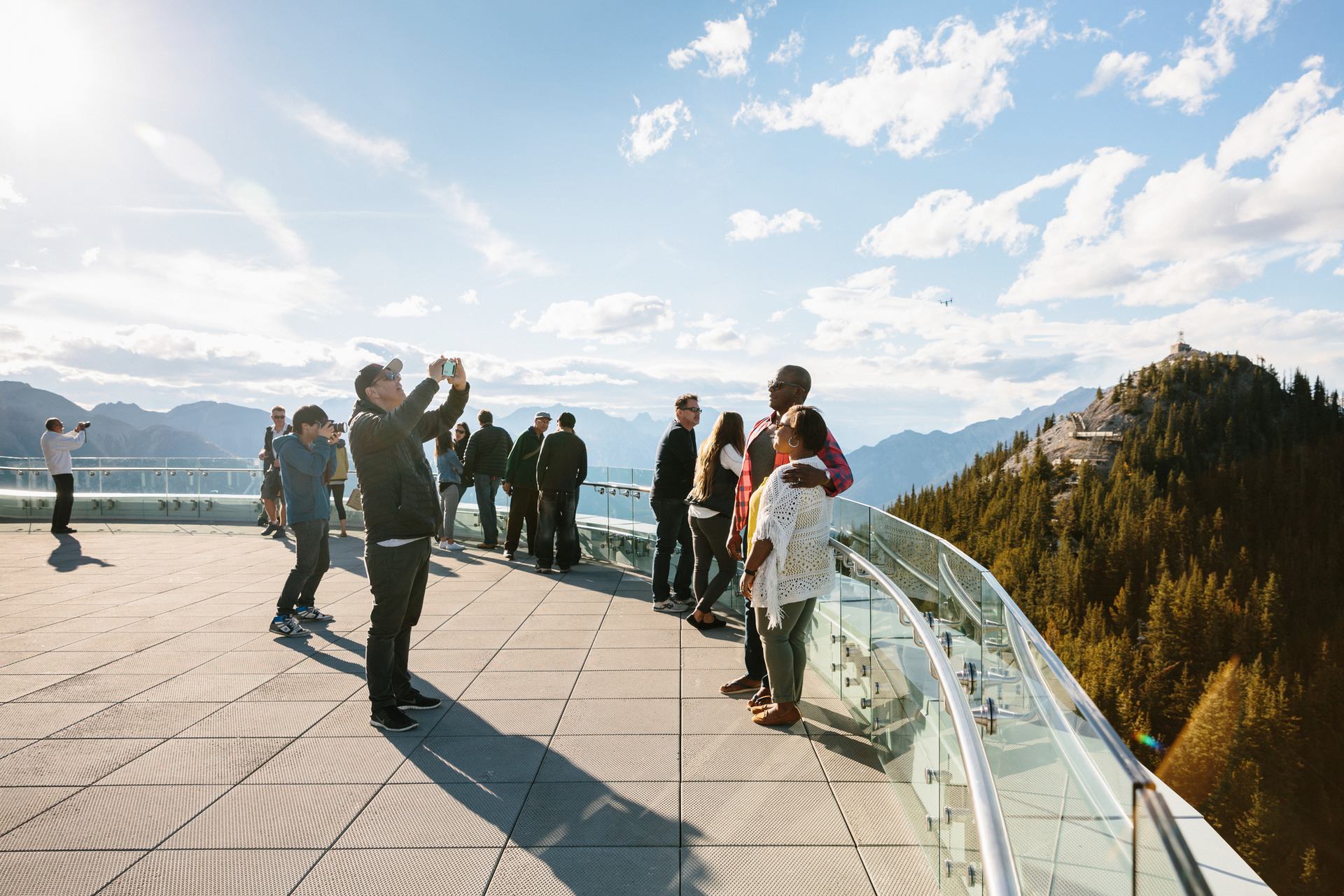 People enjoying mountain views from a scenic summit lookout with blue sky.