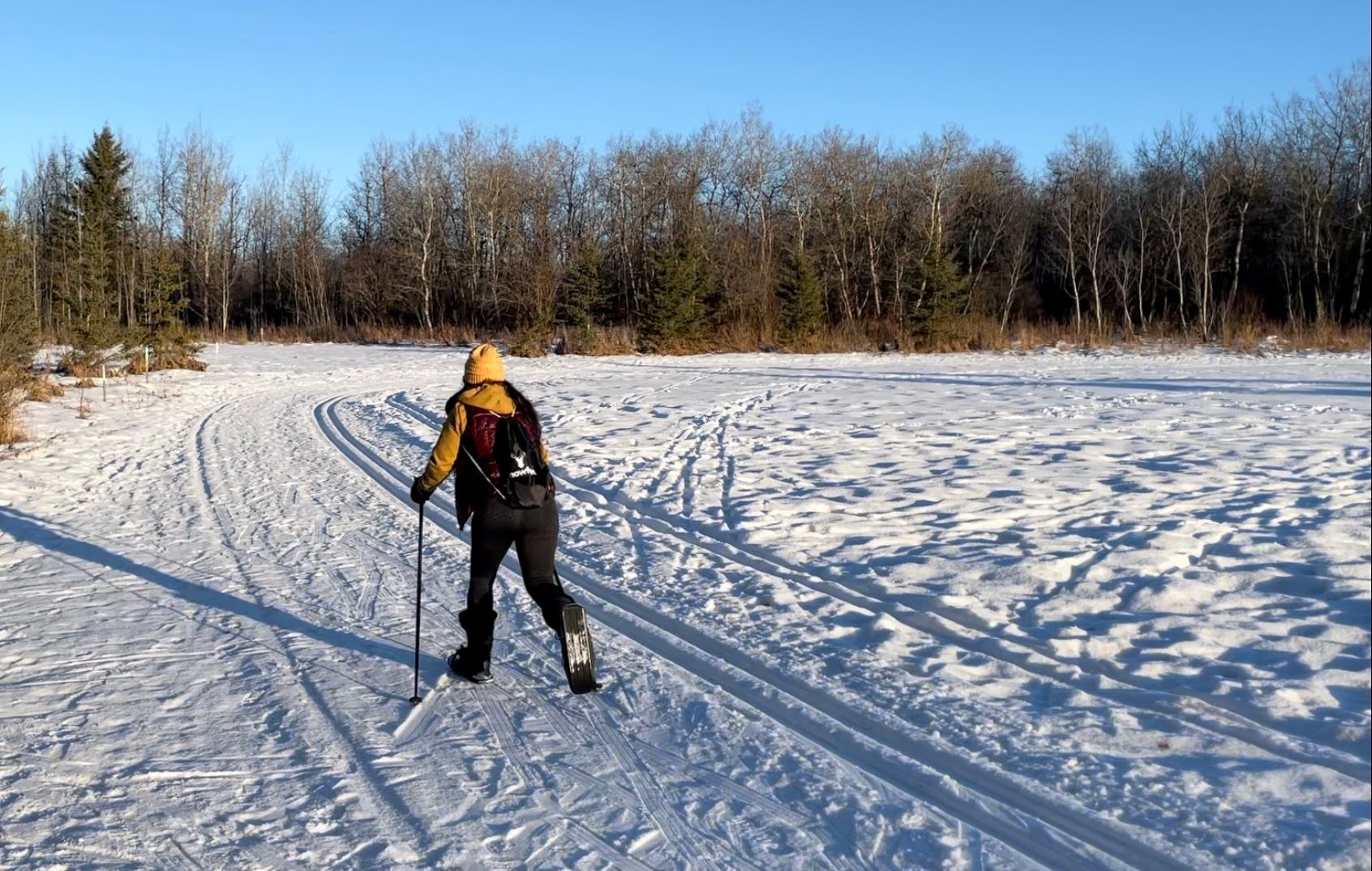 Person using Snowfeet mini skis on a snowy open field with trees in the background.
