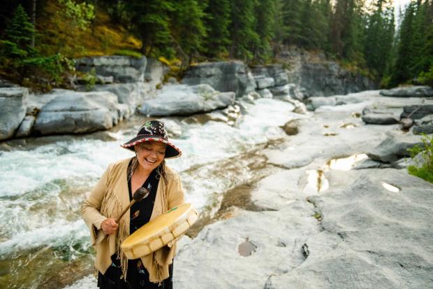 Women striking drum near river at Warrior Women.