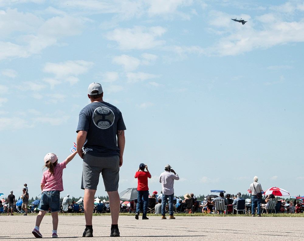 A group of people standing looking up at the sky at the airshow.