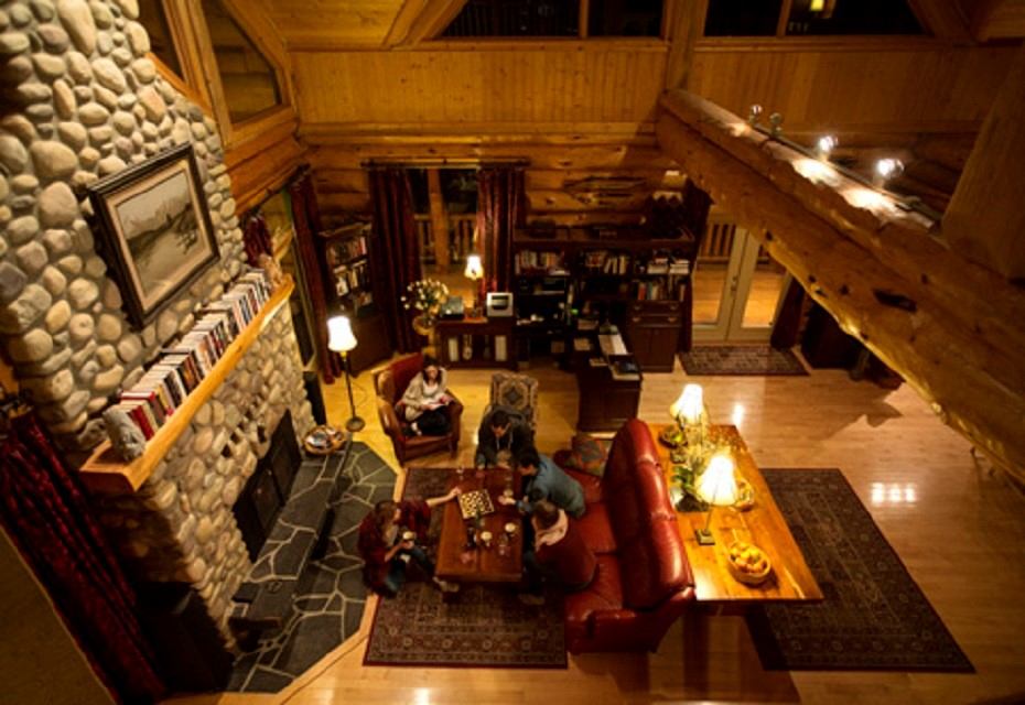 Riverside Chateau living room with stone fireplace, red sofas, and wood interior.