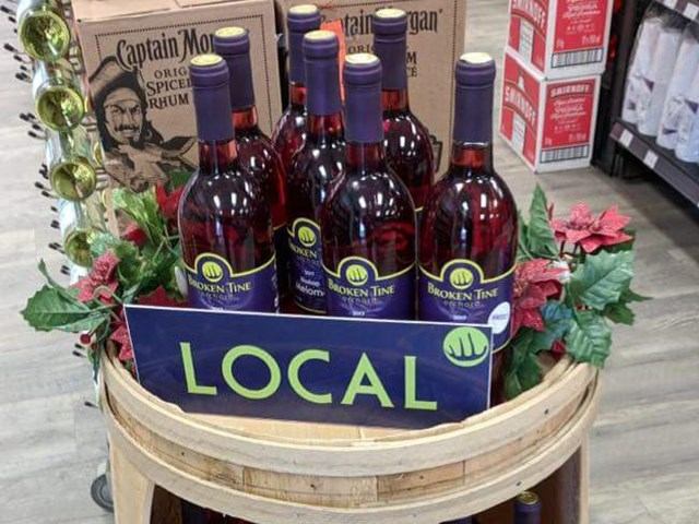 Bottles of Broken Tine Orchard wine arranged on a store display labeled “Local.”