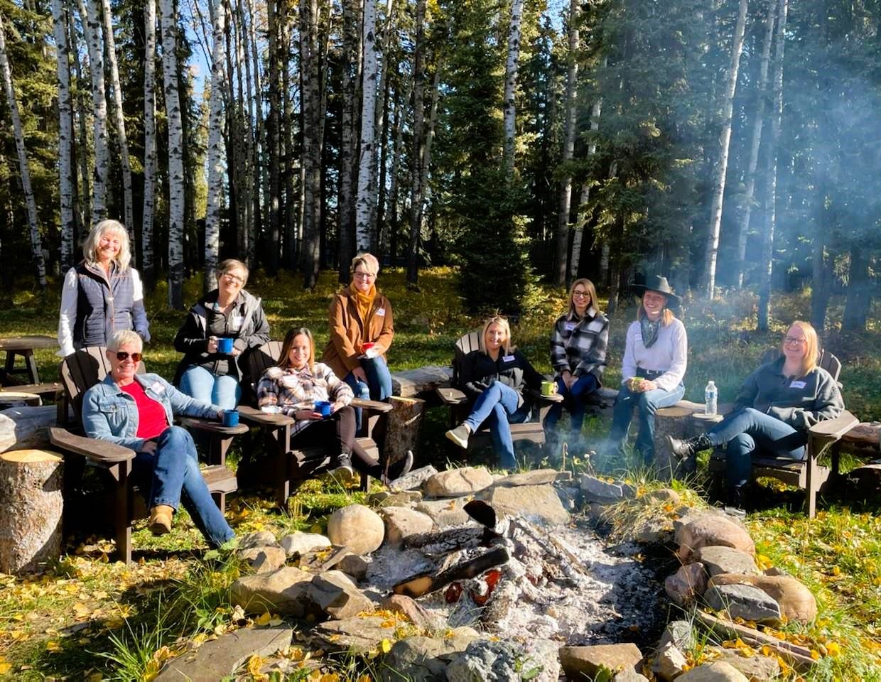 A group of women sat around a fire pit.
