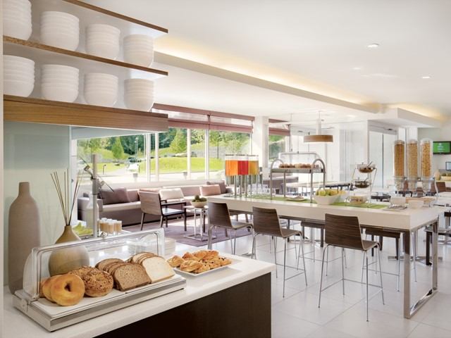 Buffet with pastries and bread in a bright hotel dining area with large windows.