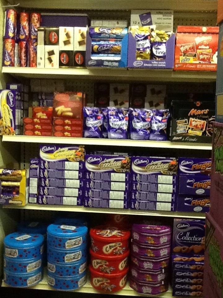 Store shelf displays candy boxes, snack bags, and jar containers in multiple rows.