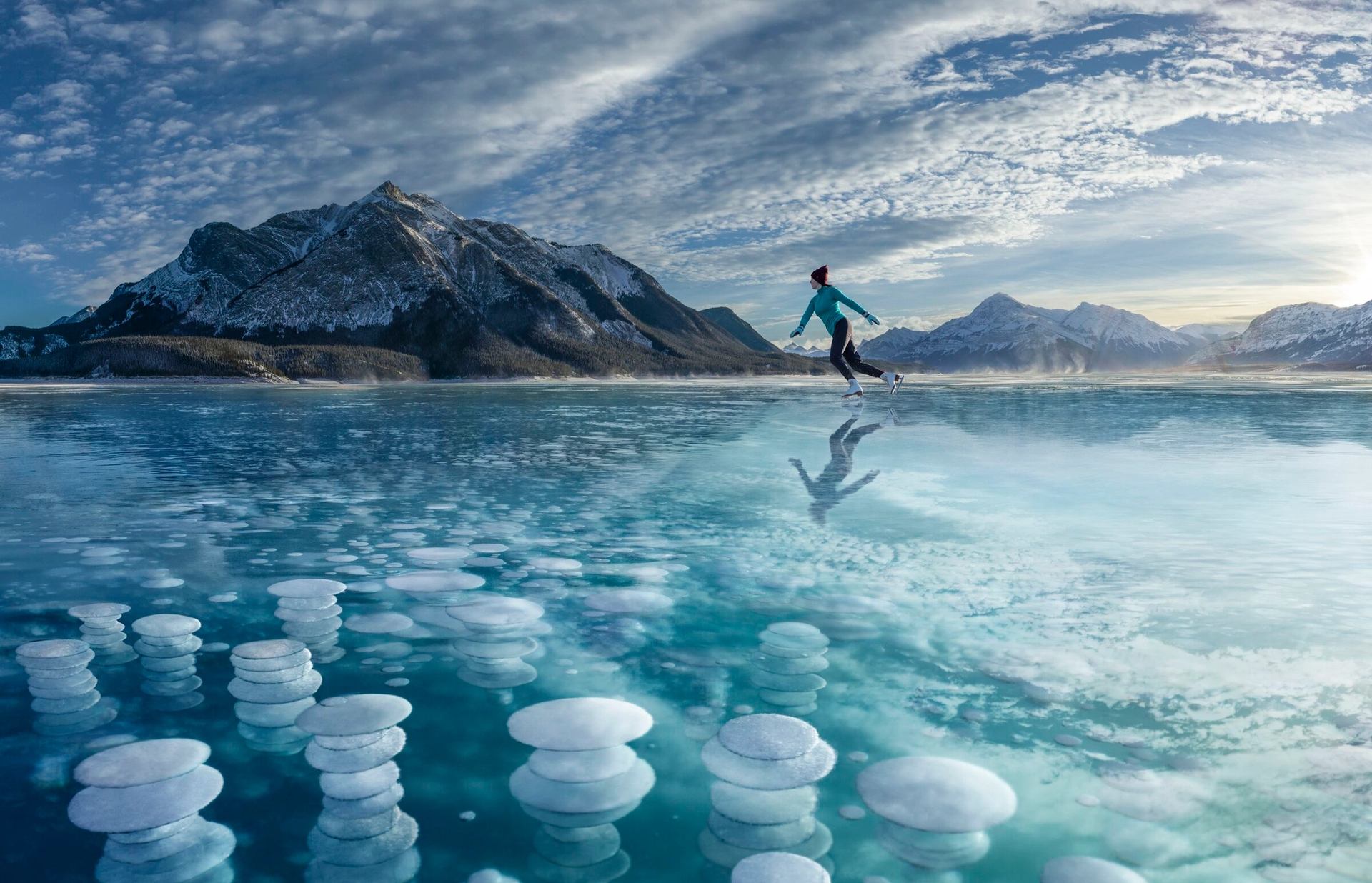 Person ice skating on Abraham Lake with frozen bubbles.