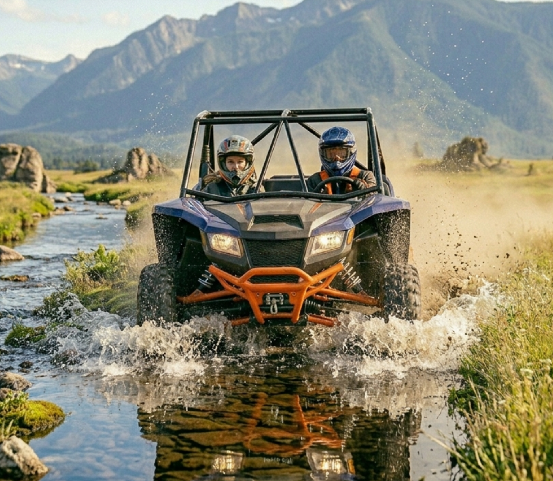 Helmeted riders drive an off-road vehicle through a stream beneath rugged mountains.