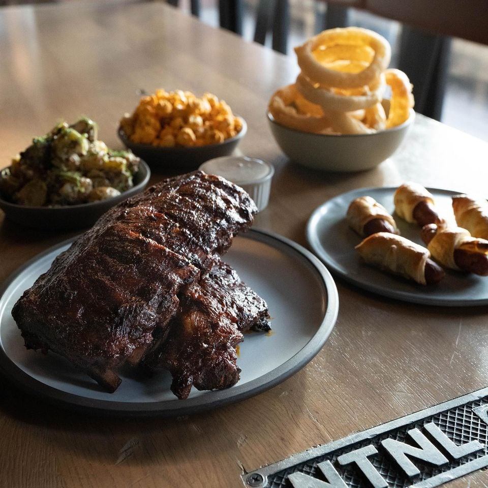 Plate of grilled ribs served with onion rings, pretzels, and vegetables