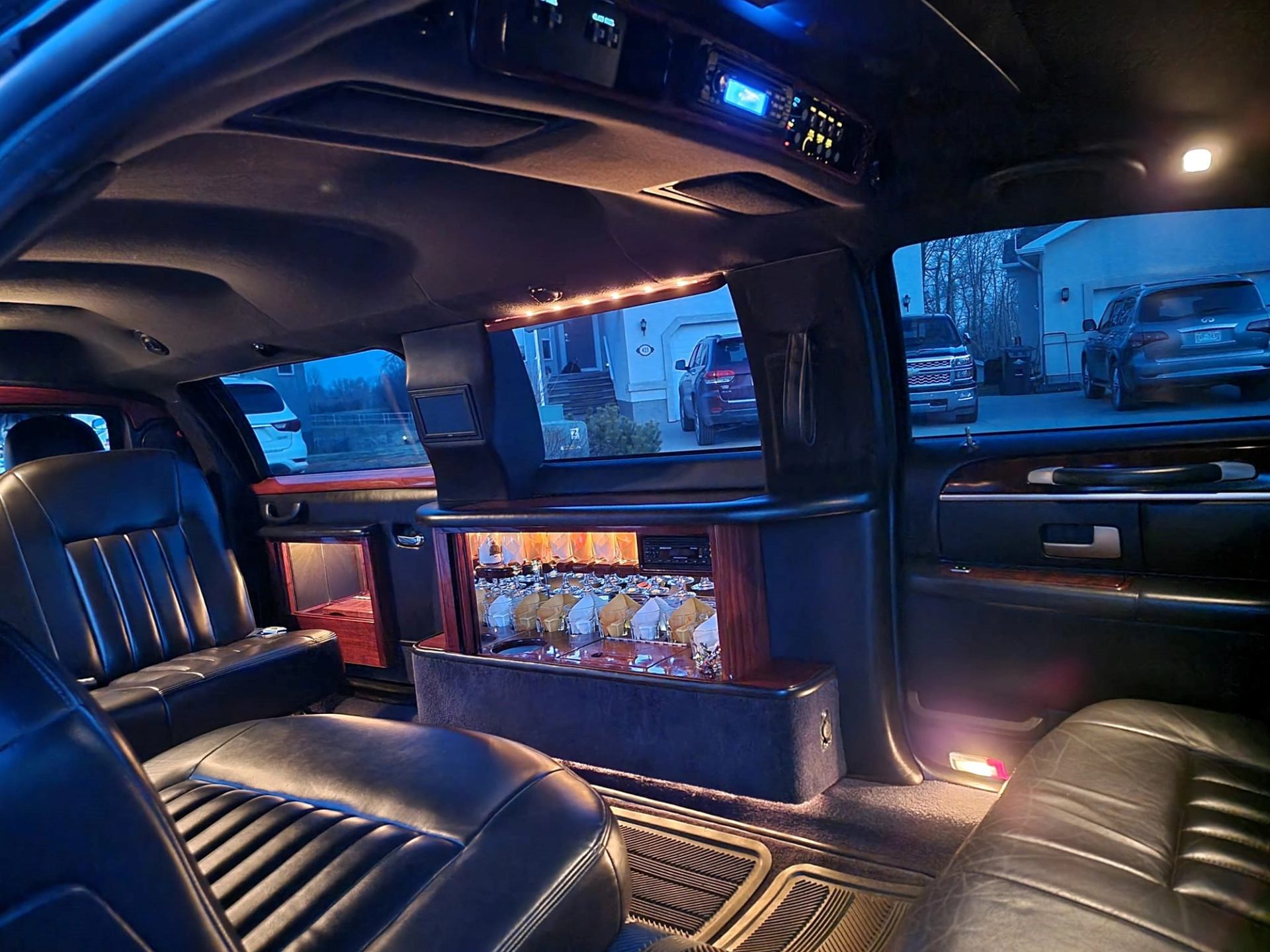 Interior of MC Limousine with leather seats, bar, and lighting.