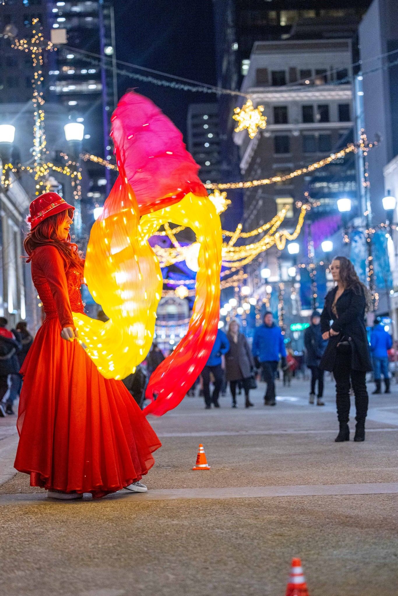 Performer in red dress spinning lighted fabric on street