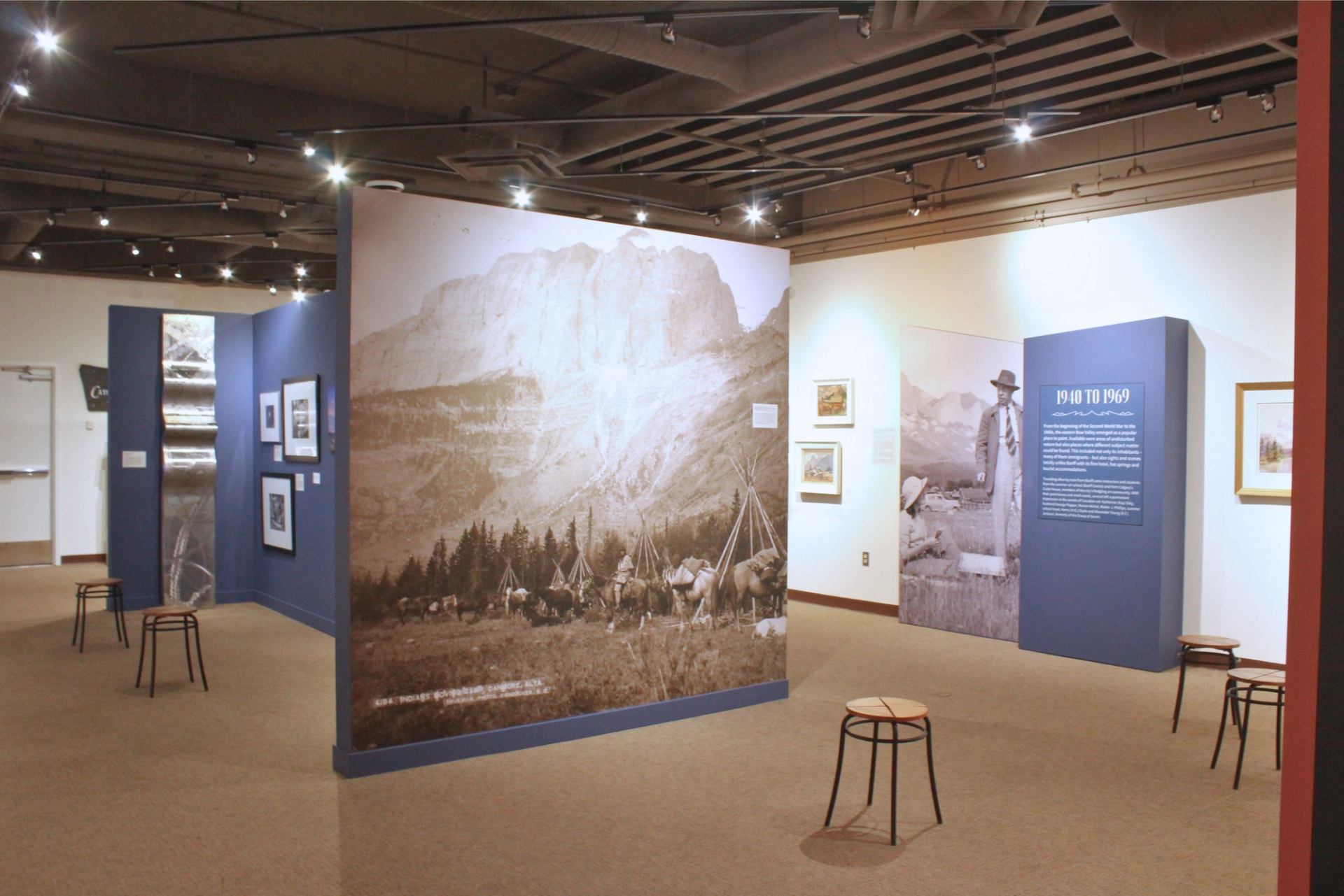 Art gallery with historical photos, blue panels, and seating in a bright, spacious, and well-lit setting.