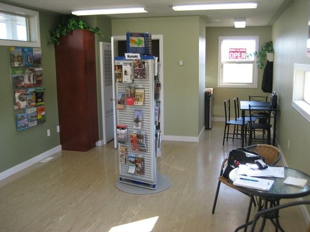 Interior of Bow Island VIC with brochure racks, tables, chairs, and an 'OPEN' sign in the window.