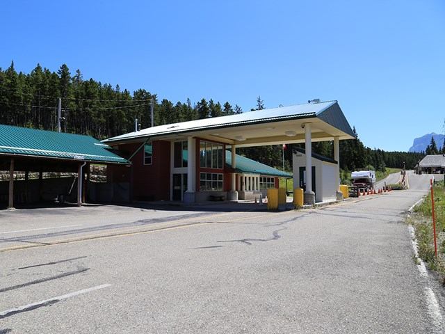 Border control booth in mountain setting with trees and blue sky.