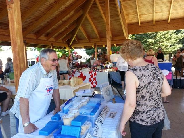 Vendor table with packaged items and signs inside a wooden pavilion at the market