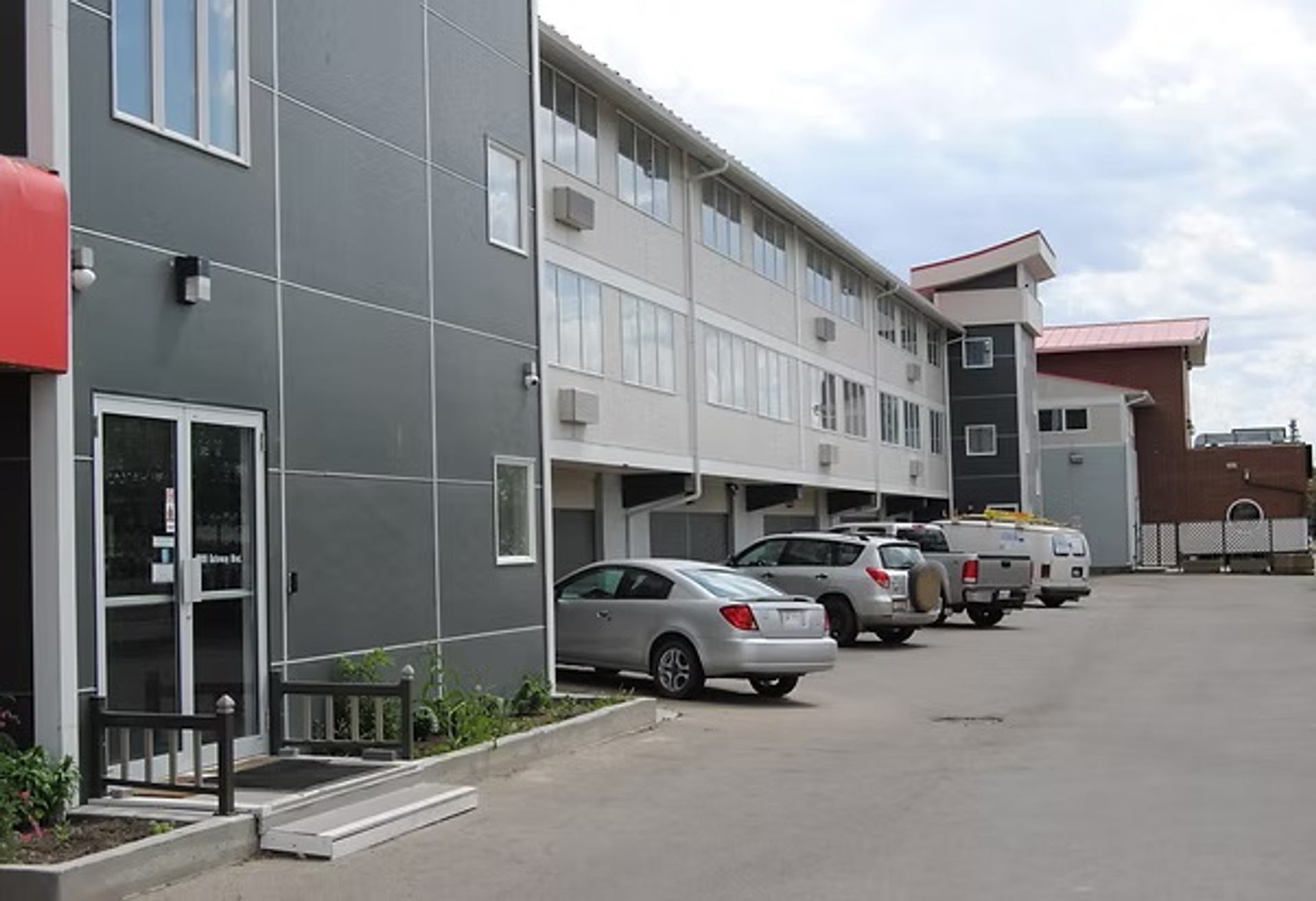 The exterior of Economy Inn Edmonton features guest parking beside a modern multi-storey building.